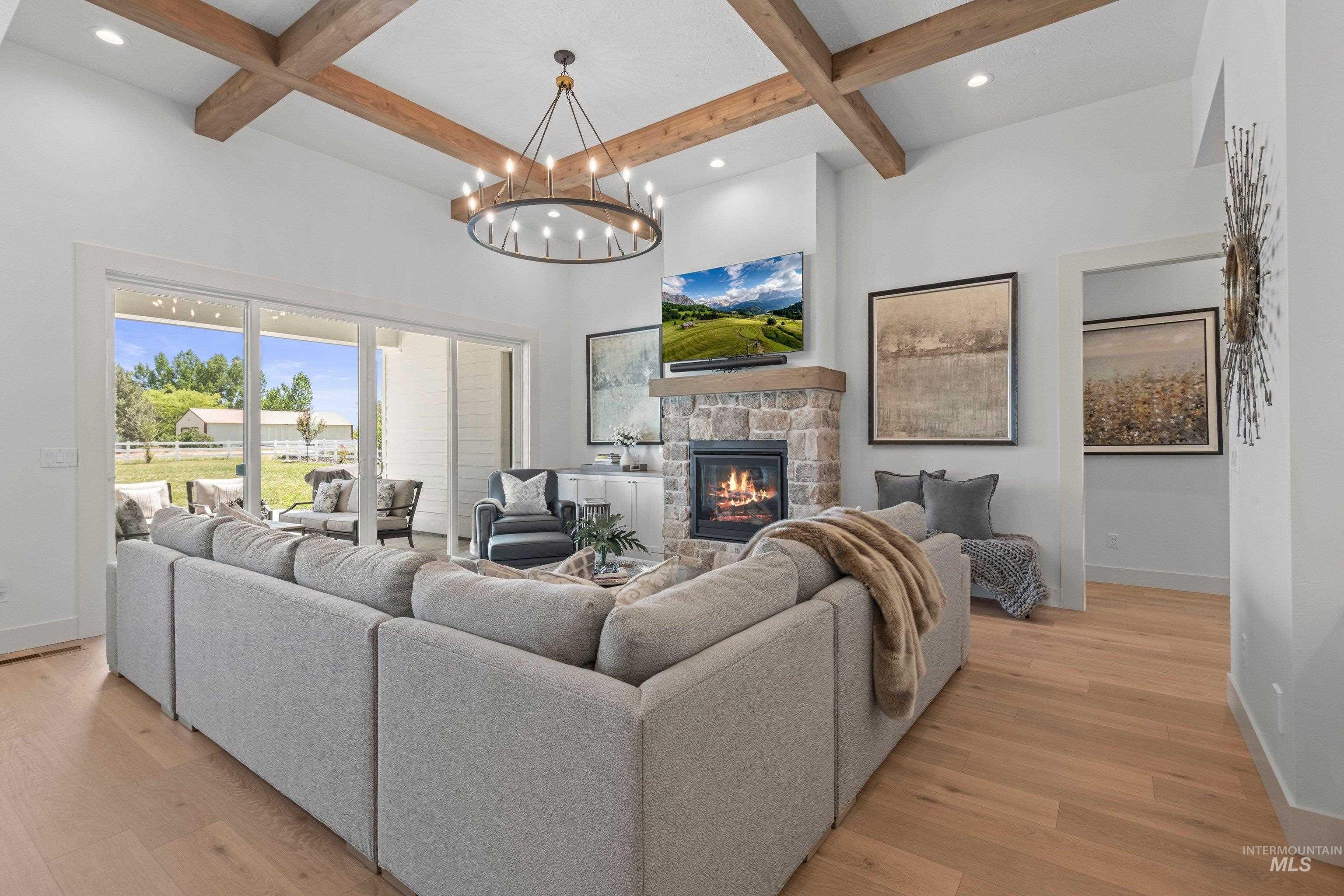 24990 Belgian Way Middleton, ID 83644 - Photo 10 of 50 Vaulted ceiling living area featuring wood-finish beams, a large chandelier, and wide plank wood-finish flooring