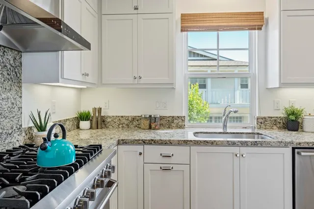 a kitchen with stainless steel appliances granite countertop a sink and a white cabinets