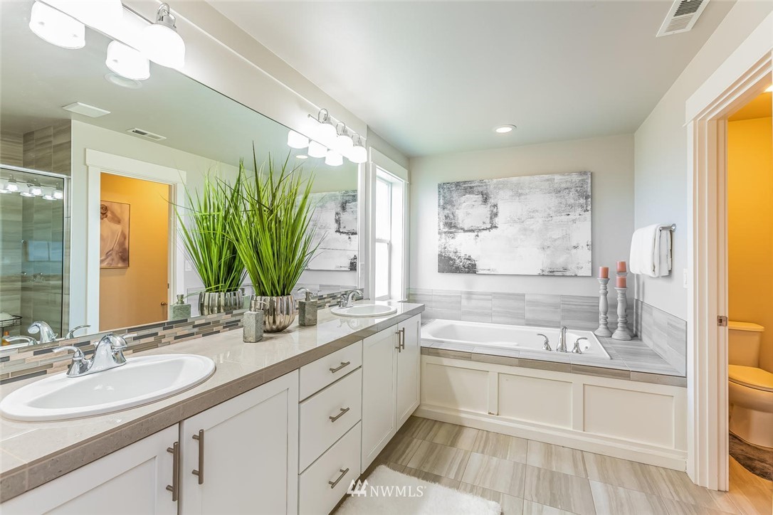 5638 Northeast 9th Street Renton, WA 98059 - Photo 21 of 40 a bathroom with a double vanity sink a mirror and a bathtub