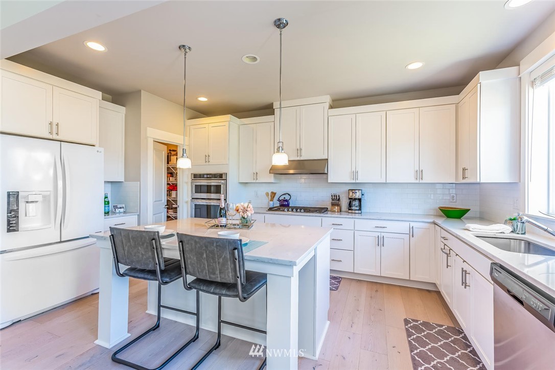 5638 Northeast 9th Street Renton, WA 98059 - Photo 5 of 40 a kitchen with stainless steel appliances granite countertop a refrigerator a sink dishwasher a stove and white cabinets with wooden floor