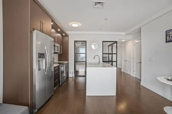 a view of a kitchen refrigerator and wooden floor
