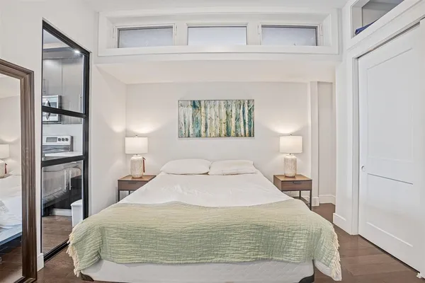 a large bed sitting in a bedroom next to a window and a wooden floor