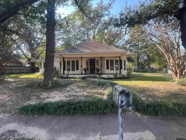 a front view of a house with garden and trees