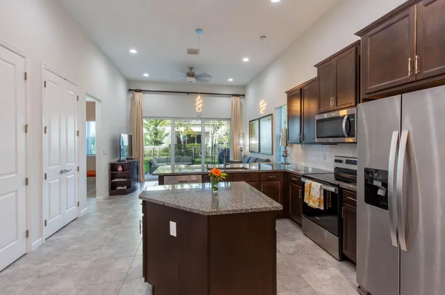 a kitchen with stainless steel appliances granite countertop a refrigerator a sink dishwasher a stove and white cabinets