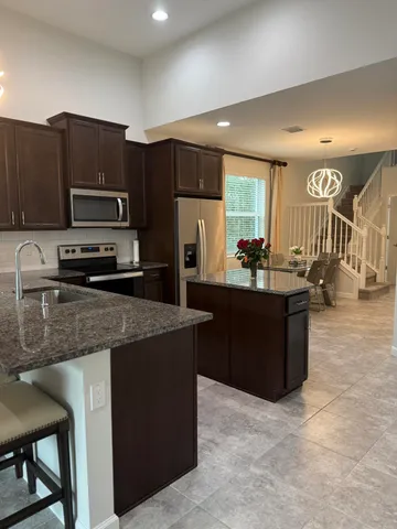 a kitchen with stainless steel appliances wooden cabinets a refrigerator a stove a sink a dining table and chairs