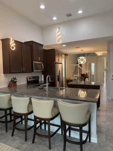 a kitchen with stainless steel appliances granite countertop a table chairs sink and cabinets