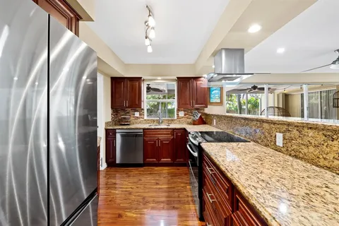 a large kitchen with stainless steel appliances granite countertop a refrigerator a stove and a sink