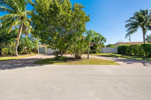 a view of a house with a yard and palm trees