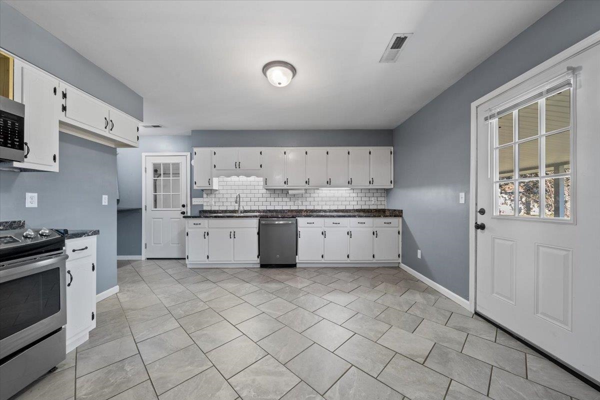 9496 Holly Grove Road Brighton, TN 38011 - Photo 10 of 29 Kitchen featuring decorative backsplash, stainless steel appliances, white cabinets, and light tile patterned floors