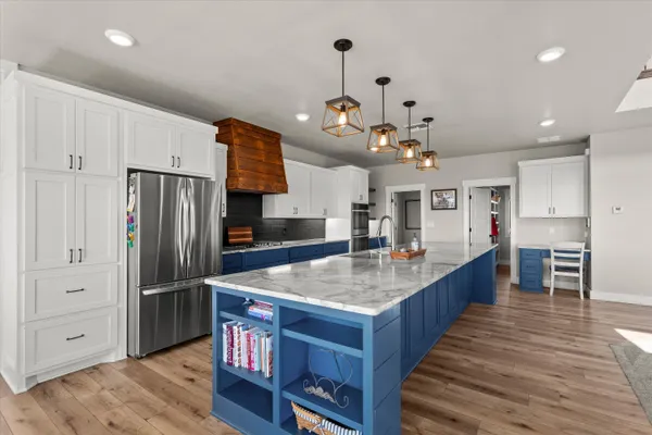 a kitchen with stainless steel appliances granite countertop a sink a stove and a wooden floor