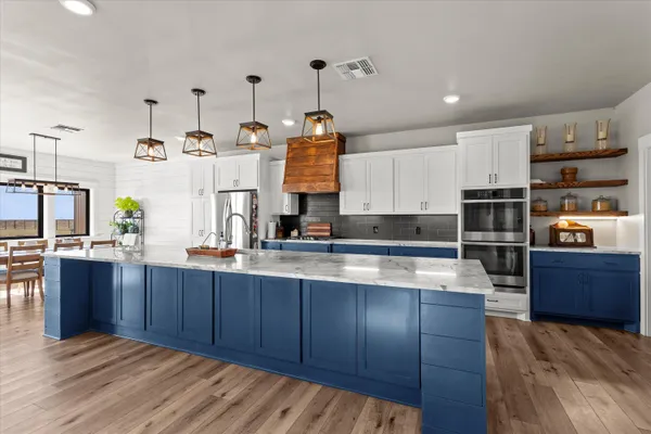 a large kitchen with stainless steel appliances granite countertop a lot of counter space and wooden floors