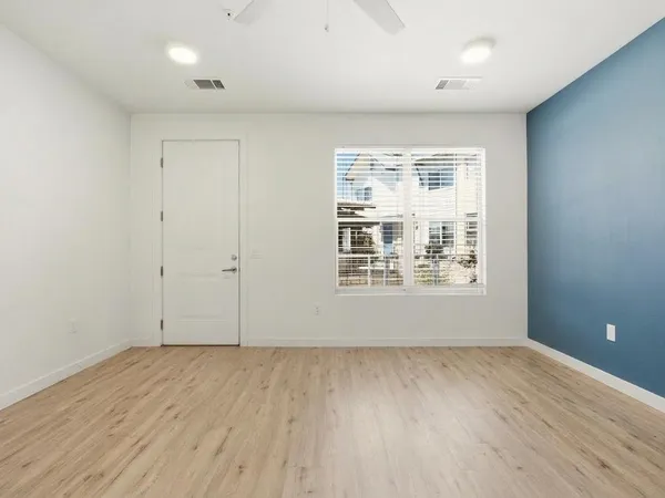 an empty room with wooden floor and windows