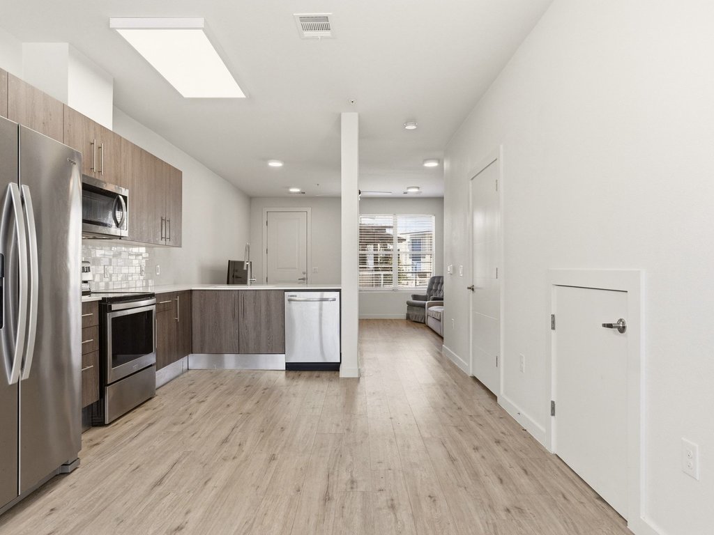 7805 Cooper Lane, Unit 608 Austin, TX 78745 - Photo 10 of 31 a large kitchen with a wooden floor and stainless steel appliances