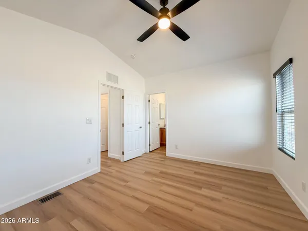 a view of empty room with wooden floor and fan