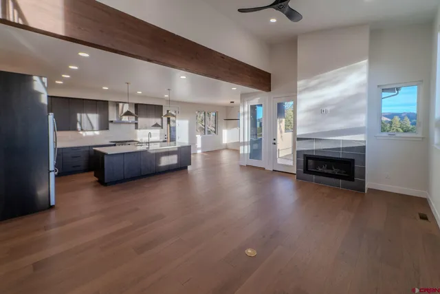 a living room with stainless steel appliances furniture a fireplace and a kitchen view