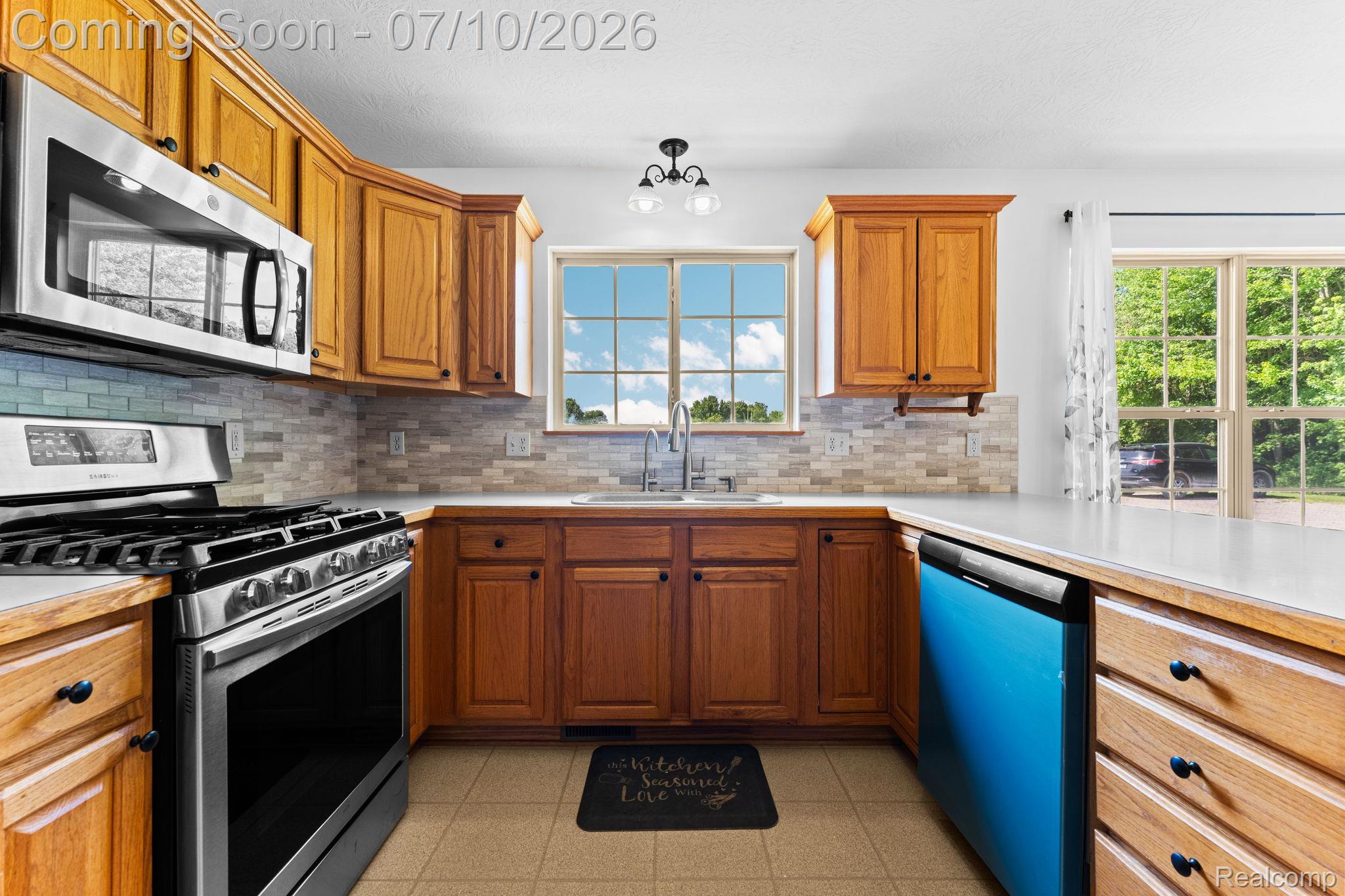 3144 North Nicholson Road Fowlerville, MI 48836 - Photo 41 of 70 Kitchen featuring wood cabinetry, stainless steel appliances, neutral countertop surfaces, and a tiled backsplash