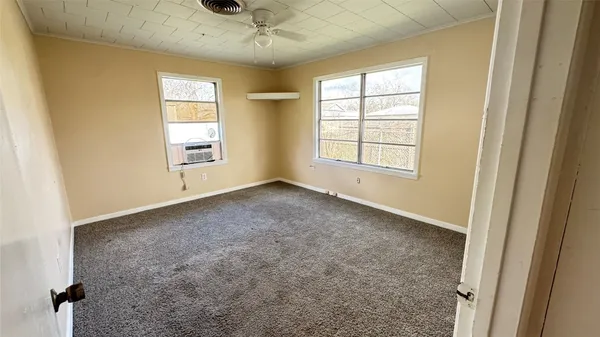 en empty room with windows and chandelier fan