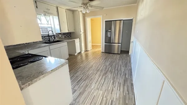 a kitchen with stainless steel appliances granite countertop a refrigerator a sink dishwasher a stove and white countertops with wooden floor