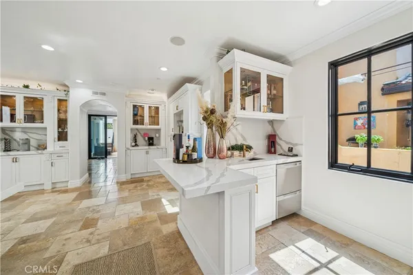 a large white kitchen with granite countertop a sink and cabinets