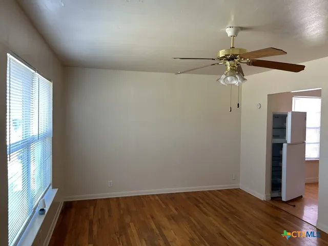 an empty room with a window and a ceiling fan