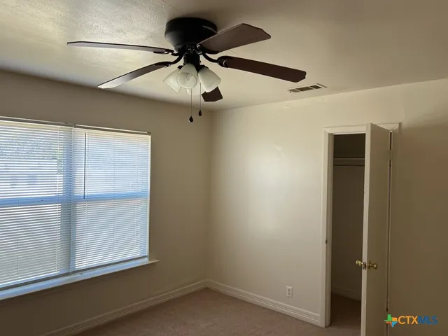 an empty room with a window and a ceiling fan