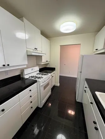 a kitchen with granite countertop white cabinets and white appliances