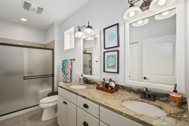 a bathroom with a granite countertop double vanity sink mirror and toilet