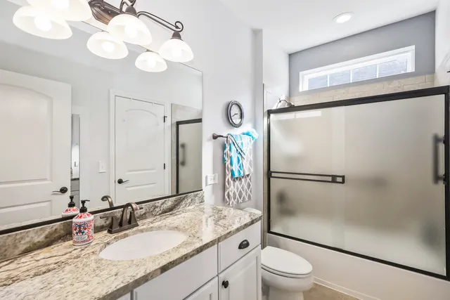 a bathroom with a granite countertop sink toilet a mirror and shower