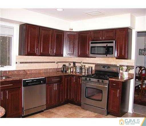 184 Plainfield Road Edison, NJ 08820 - Photo 4 of 12 a kitchen with granite countertop a stove top oven microwave and cabinets