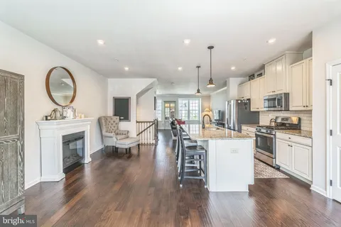 a living room with stainless steel appliances furniture a fireplace a rug kitchen view and a fireplace