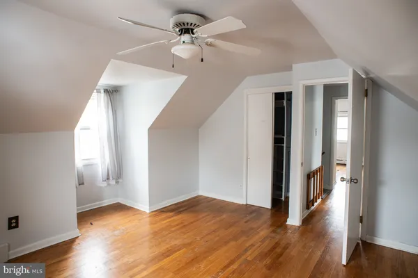 a view of a hallway with wooden floor and a ceiling fan