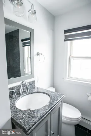 a bathroom with a granite countertop sink and a toilet