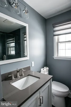 a bathroom with a granite countertop sink a large mirror and a toilet