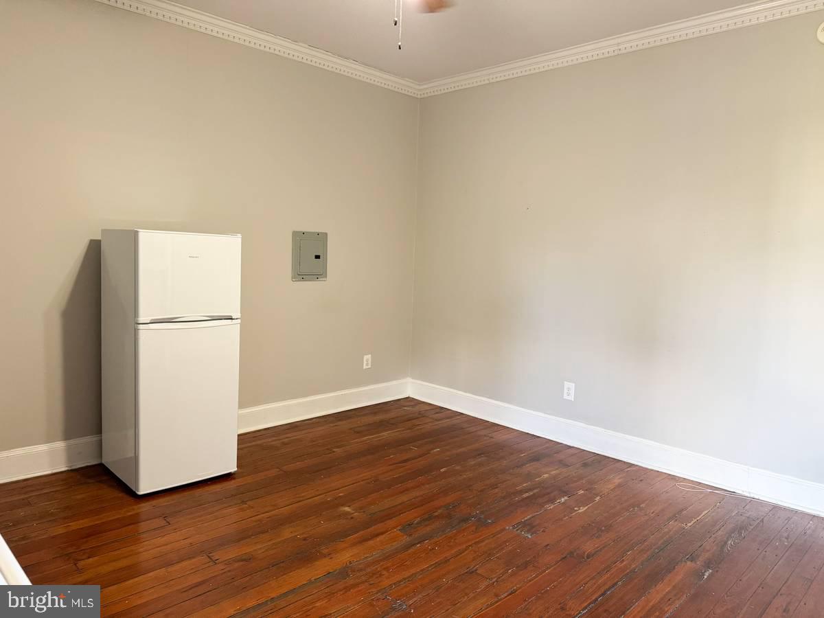 2209 Walnut Street, Unit 3M Philadelphia, PA 19103 - Photo 6 of 7 a view of an empty room with wooden floor and a refrigerator