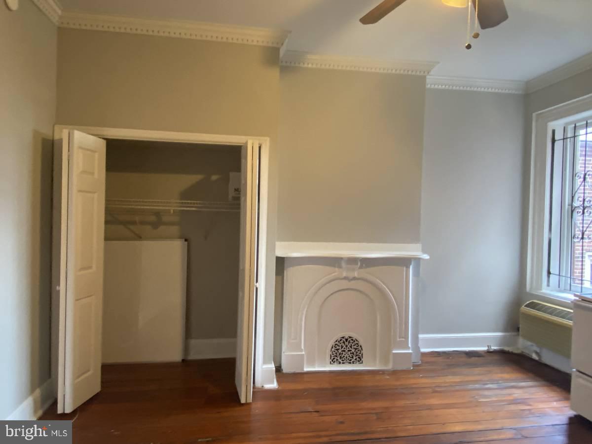 2209 Walnut Street, Unit 3M Philadelphia, PA 19103 - Photo 7 of 7 a view of an empty room with wooden floor kitchen view and a fireplace