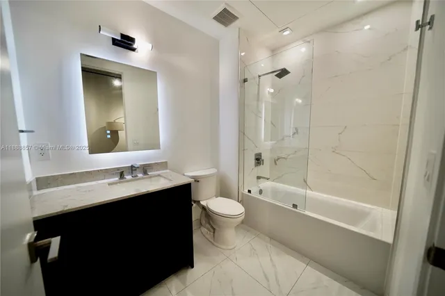 a bathroom with a double vanity sink toilet mirror and shower