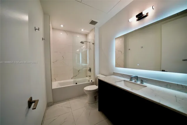 a bathroom with a double vanity sink toilet mirror and bathtub
