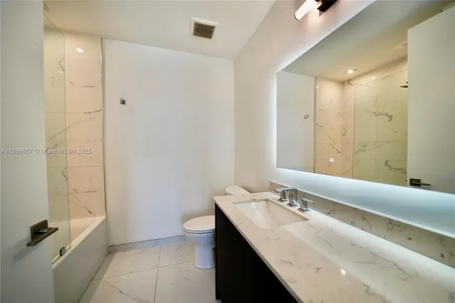 a bathroom with a granite countertop sink a toilet and shower