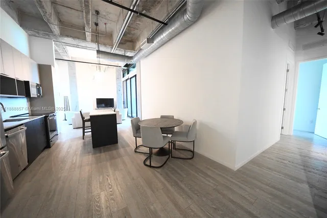 a view of a dining room with furniture a kitchen and wooden floor