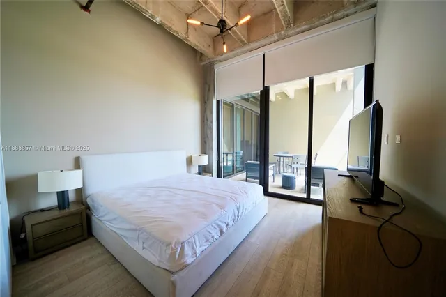 a bedroom with a bed window table and flat screen tv