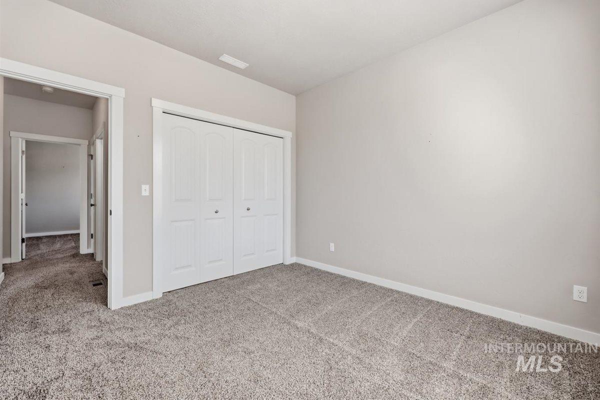 13496 Hockberger Ranch Road Caldwell, ID 83607 - Photo 12 of 40 Neutral-toned wall paint with white trim, gray carpet flooring, and a white bi-fold closet door