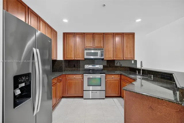 a kitchen with stainless steel appliances granite countertop a refrigerator sink and stove