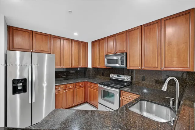 a kitchen with stainless steel appliances granite countertop a refrigerator sink and stove