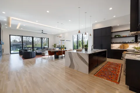 a living room with furniture kitchen view and a chandelier