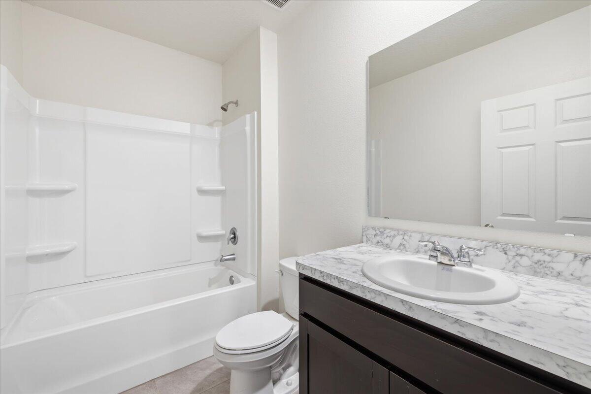 1072 Roseland Road Sebastian, FL 32958 - Photo 32 of 47 a bathroom with a granite countertop sink a toilet a mirror a bathtub and shower