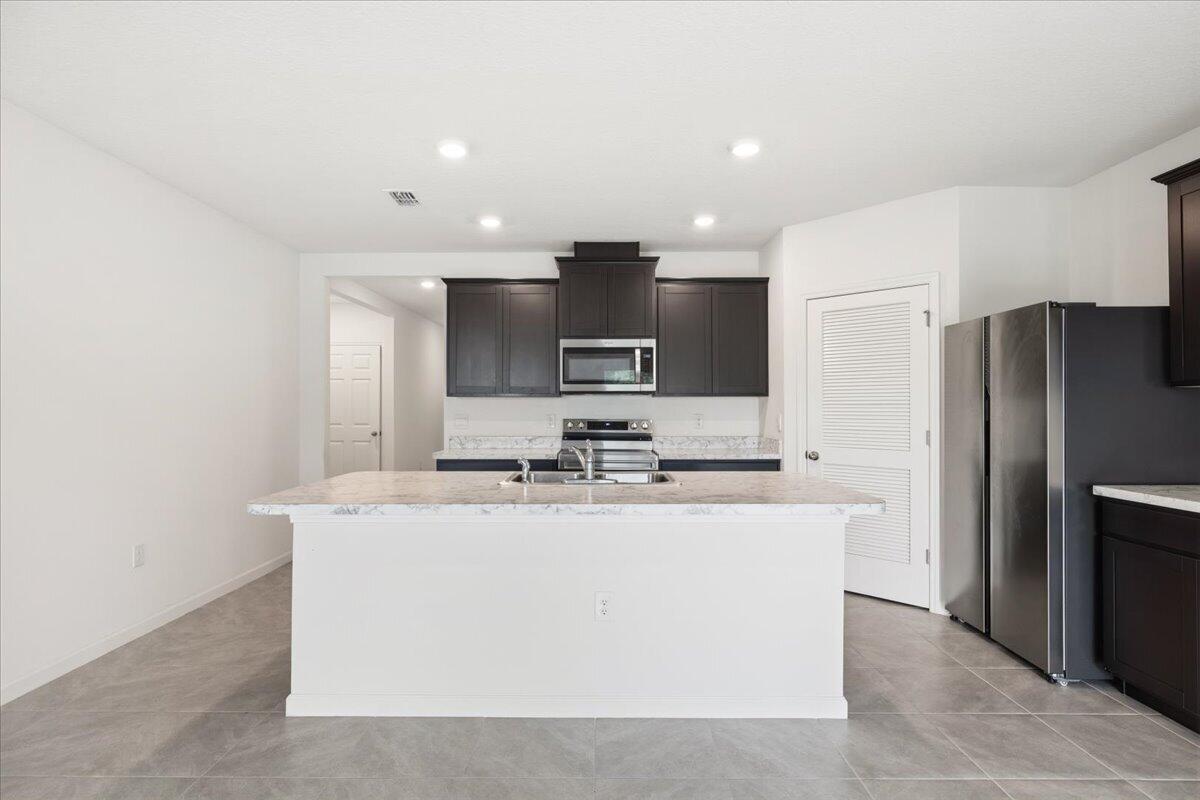 1072 Roseland Road Sebastian, FL 32958 - Photo 10 of 47 a kitchen with kitchen island stainless steel appliances a sink and a refrigerator