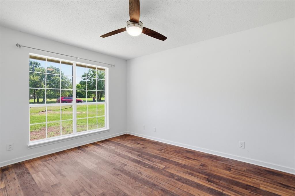 1974 County Road Powderly, TX 75473 - Photo 19 of 28 an empty room with wooden floor and windows