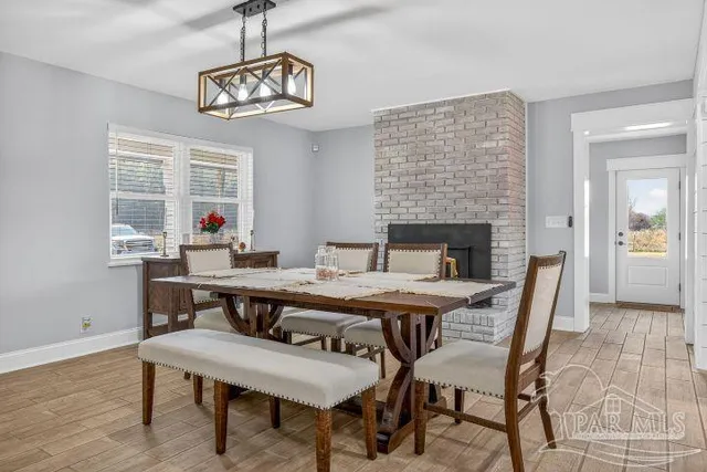 a living room with stainless steel appliances furniture a fireplace and a ceiling fan