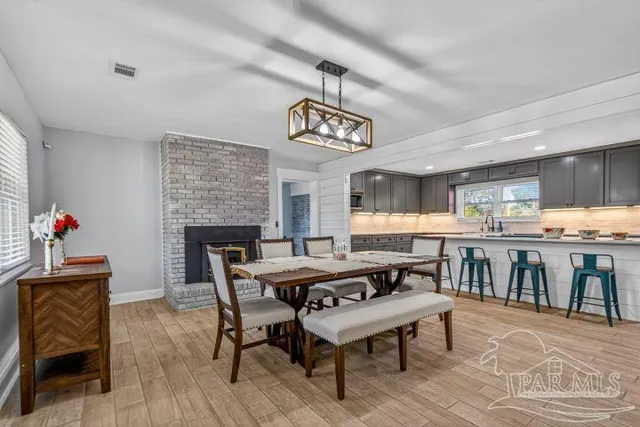 a kitchen with stainless steel appliances granite countertop wooden cabinets a refrigerator a sink a stove a dining table and chairs