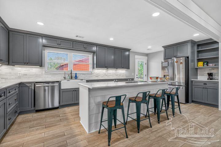 8940 Indian Ford Road Milton, FL 32570 - Photo 22 of 54 a kitchen with stainless steel appliances granite countertop wooden cabinets a refrigerator a sink a stove a dining table and chairs
